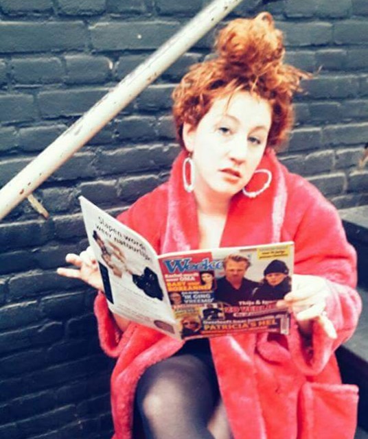 Tina Brouwers in een rol met rode jas en tijdschrift